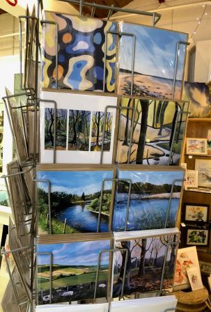 A selection of colourful greetings cards of Judy Randle's acrylic paintings of landscapes including Ecclesall Woods, Yorkshire moorland, the River Spey and a deserted sandy beach.