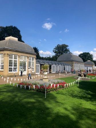 Victorian glass houses at Sheffield Botanical Gardens on a sunny day in September 2023. The sky is blue and the bunting colourful.