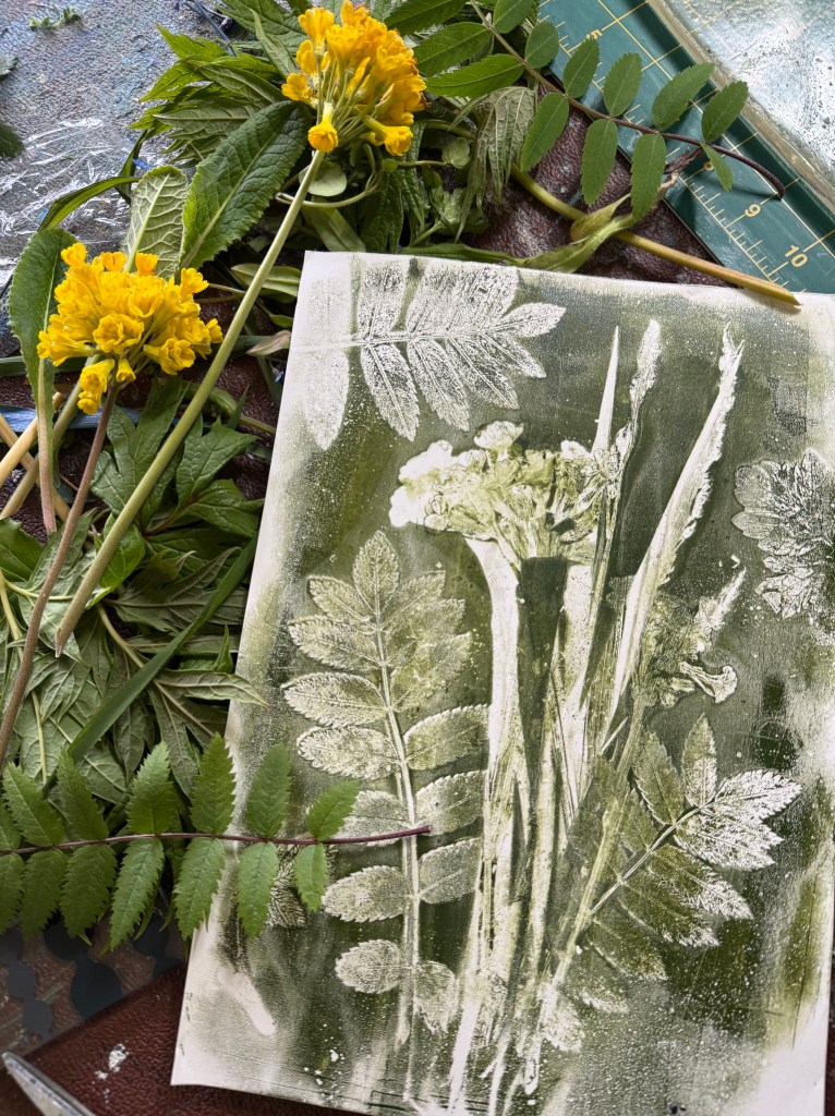 A green gelli plate print next to grasses and cowslips 