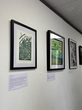 A gallery wall with a green lino print of Sheffield Winter Gardens in the foreground