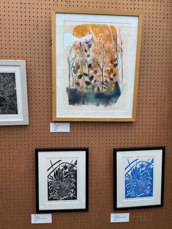 A framed golden gelliprint and 2 lino prints in an art exhibition 