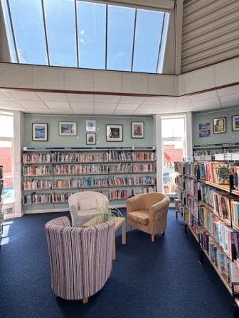 A library with comfortable armchairs, a blue carpet and an exhibition of framed giclee prints by Judy Randle on the wall